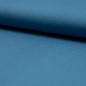 May include: A close-up of a smooth, solid blue fabric. The fabric is folded in half, showing the texture and color.