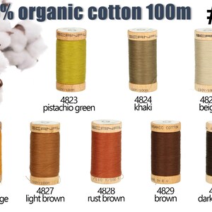 K&ouml;nnte beinhalten: Acht Garnrollen aus 100% Bio-Baumwolle, je 100m lang, beschriftet mit den Nummern 4823 bis 4830 und den Farbnamen Pistaziengr&uuml;n, Khaki, Beige, Dunkelorange, Hellbraun, Rostbraun, Braun und Dunkelbraun, dazu abgebildete Baumwollbl&uuml;ten.