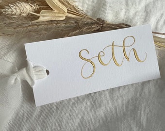 Plaatskaarten met gouden inktkalligrafie: witte kaart met lint