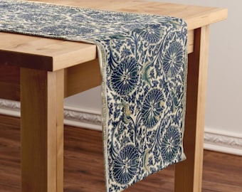 Puede incluir: Un camino de mesa azul marino y crema con un patrón floral. El camino de mesa tiene un ribete dorado y está sobre una mesa de madera.