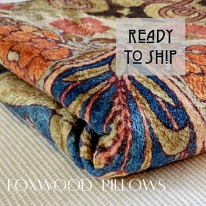 May include: A folded fabric with a blue, orange, and brown paisley pattern. The fabric is labeled "Foxwood Pillows" and has a white label that says "Ready to Ship".