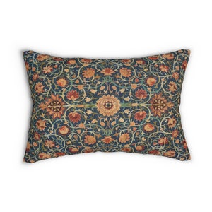 Può includere: Un cuscino rettangolare con sfondo blu e un motivo floreale in tonalità arancio, rosso e giallo. Il motivo è intricato e presenta foglie, fiori e forme geometriche.