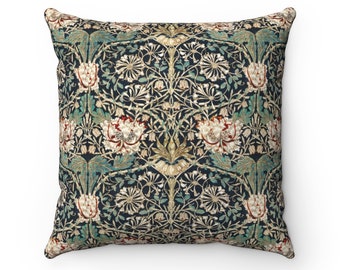 Pode incluir: Almofada quadrada com um padrão floral em tons de azul marinho, creme, verde-azulado e ferrugem. O design apresenta flores e folhagens estilizadas, criando uma estética vintage. A almofada é provavelmente feita de um tecido macio, perfeita para adicionar um toque decorativo.