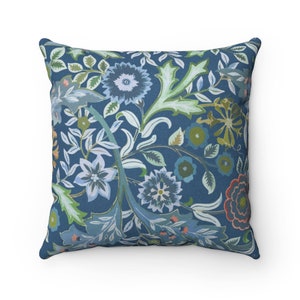 Pode incluir: Uma almofada azul com um padrão floral que apresenta folhas verdes, flores azuis e brancas e acentos vermelhos e laranja.