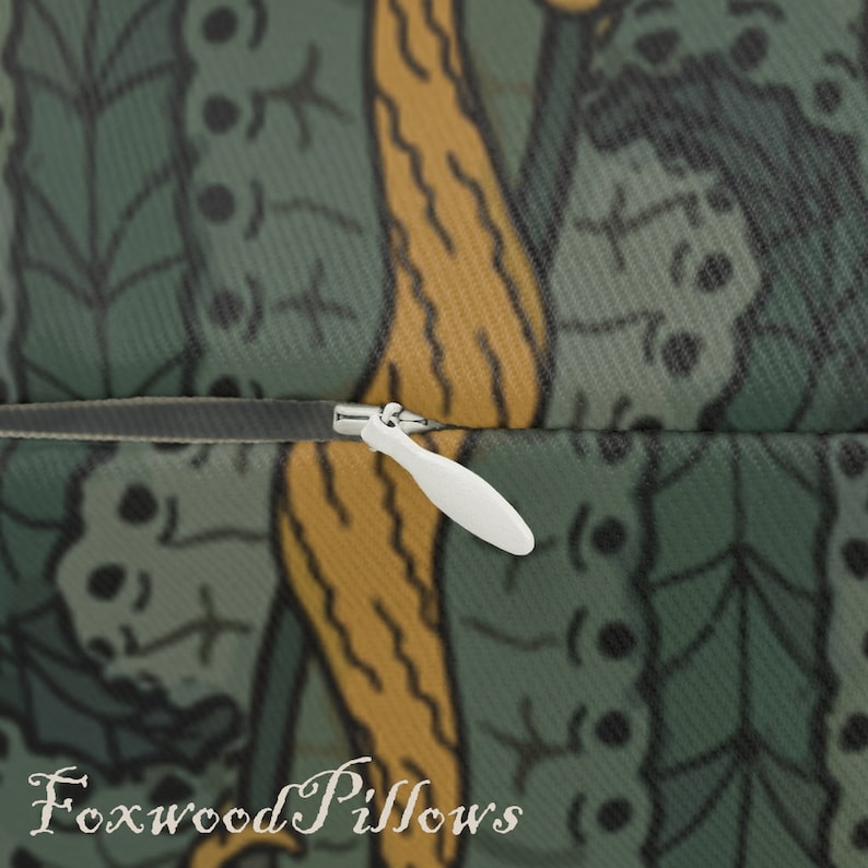 May include: Close-up of a zipper on a green and yellow patterned pillow cover. The zipper is white and has a pull tab. The pillow cover is made of a soft, comfortable fabric. Foxwood Pillows is printed on the bottom of the image.