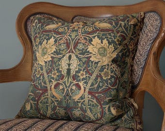 May include: A square cushion with a detailed floral design in green, gold, and burgundy. The cushion is on a wooden chair with a striped seat, creating a vintage aesthetic. The cushion is approximately 40cm x 40cm.