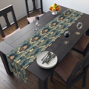 May include: A dark wooden dining table set with a patterned table runner, white plates, silverware, wine glasses, and a bowl of fruit. The table runner has a geometric design in shades of blue, beige, and brown.