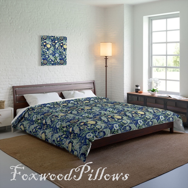 Puede incluir: Una funda n&oacute;rdica azul marino con un patr&oacute;n floral en tonos de verde, amarillo y blanco. La funda n&oacute;rdica est&aacute; en una cama con almohadas blancas y una cabecera de madera marr&oacute;n.