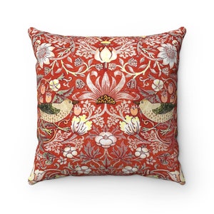 May include: Red throw pillow with a floral pattern featuring birds and stylized flowers. The pillow has a red background with white, yellow, and green accents.