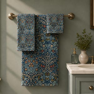 May include: A set of three rectangular towels hanging on a bronze-toned metal bar. The towels feature a dense, intricate botanical pattern with deep blue, light blue, orange, and cream-colored floral and leafy motifs across the entire fabric surface.
