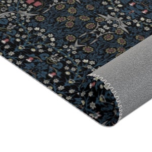 Puede incluir: Primer plano de una alfombra azul y negra con un patr&oacute;n floral. La alfombra est&aacute; enrollada y se ve el borde de la alfombra.