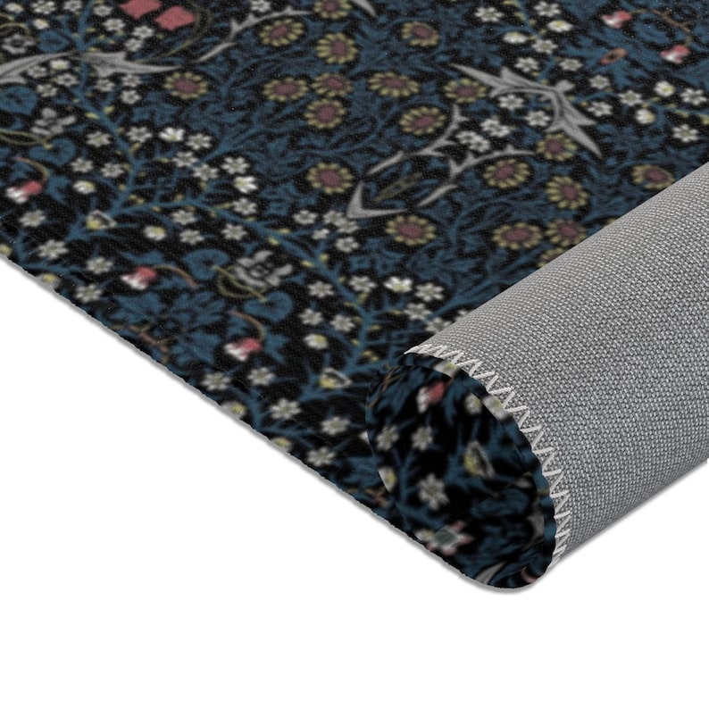 Puede incluir: Primer plano de una alfombra azul y negra con un patr&oacute;n floral. La alfombra est&aacute; enrollada y se ve el borde de la alfombra.