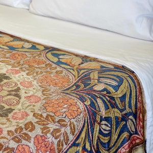 May include: A cream-colored bedspread with a floral pattern in shades of orange, brown, and blue. The pattern features stylized flowers and leaves.