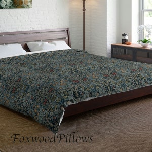 May include: A dark blue duvet cover with a floral pattern featuring red, yellow, and green accents. The duvet cover is on a bed with white pillows and a wooden headboard. The text "Foxwood Pillows" is visible in the bottom right corner of the image.