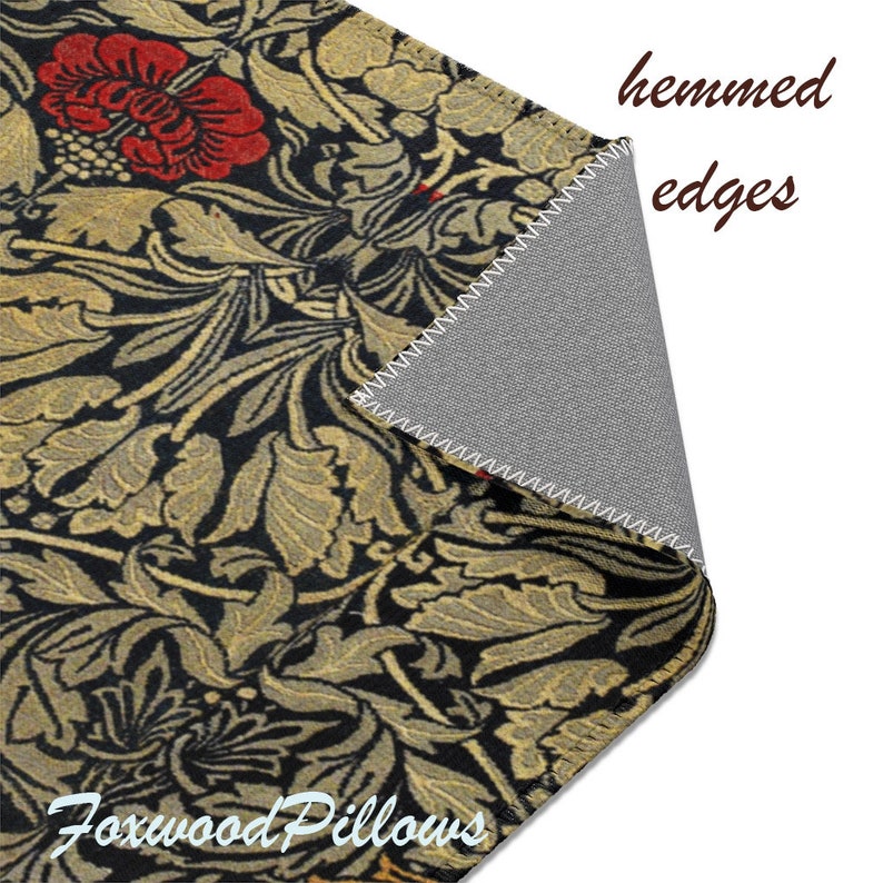 Puede incluir: Una almohada de tiro con estampado floral negro y dorado con bordes doblados. La almohada presenta un patr&oacute;n repetitivo de flores y hojas estilizadas. El texto "Foxwood Pillows" es visible en la esquina inferior derecha.