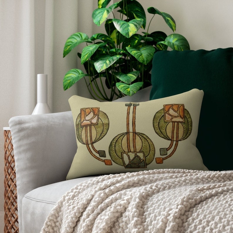 May include: A decorative throw pillow with a beige background and a stylized floral design in shades of green, brown, and orange. The design features three stylized flowers with geometric shapes and lines.