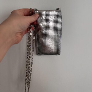 May include: A silver chain strap purse with a mesh design.
