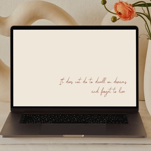 May include: A laptop computer with a white background and the text "It does not do to dwell on dreams and forget to live" in red cursive font.