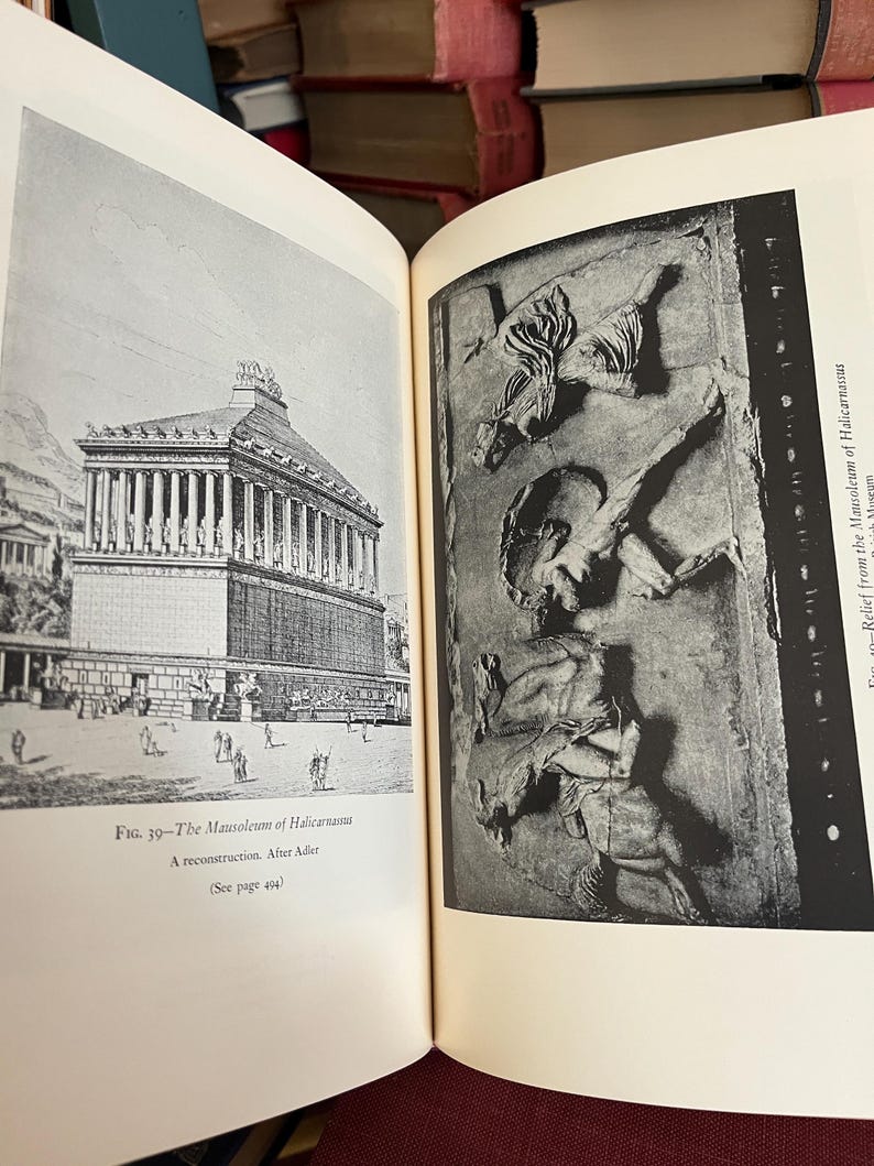 May include: Open book with two black and white illustrations. The left page shows a drawing of a large building with columns, labeled "The Mausoleum of Halicarnassus." The right page displays a relief sculpture.