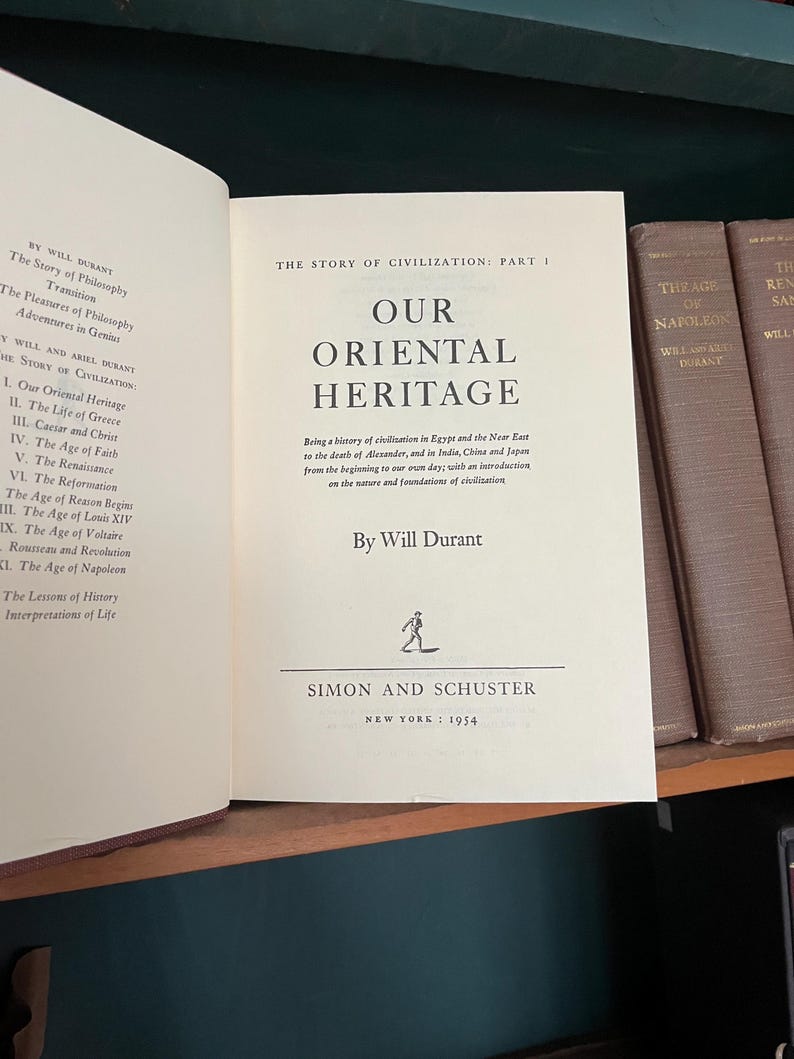 May include: Open book titled "Our Oriental Heritage" by Will Durant, published by Simon and Schuster in 1954. The book is part of "The Story of Civilization" series. The cover is a light beige color.