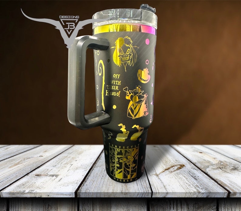 May include: Black stainless steel tumbler with a gold glitter finish and a black handle. The tumbler features a design of characters from the movie "Wicked" with the text "Off with their heads!" and "Perfectly Wicked".