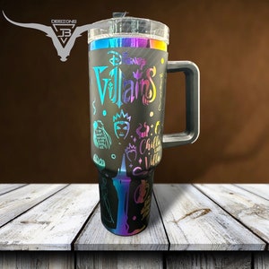 May include: A black stainless steel travel mug with a rainbow iridescent finish. The mug features a Disney Villains design with various characters and the text "Disney Villains" and "Chilla Like a Villa".