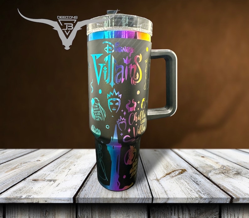 May include: A black stainless steel travel mug with a rainbow iridescent finish. The mug features a Disney Villains design with various characters and the text "Disney Villains" and "Chilla Like a Villa".