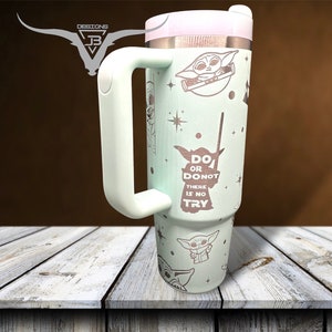 Puede incluir: Un vaso de acero inoxidable verde claro con tapa y asa blancas. El vaso presenta un patr&oacute;n repetido de un personaje de dibujos animados con el texto "Do or Do Not, There is No Try".