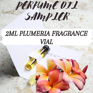 May include: A 2 ml vial of Plumeria fragrance oil perfume sampler. The vial is in a white cardboard box with the text "PERFUME OIL SAMPLER" and "2 ML PLUMERIA FRAGRANCE VIAL". The image also shows a close-up of a pink and yellow Plumeria flower.