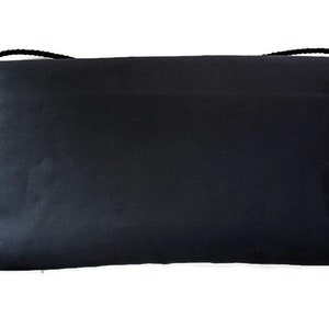 Puede incluir: Un bolso de mano rectangular negro con una correa de cuerda negra. El bolso est&aacute; hecho de un material liso, posiblemente similar al sat&eacute;n. La correa est&aacute; sujeta a las esquinas superiores del bolso.