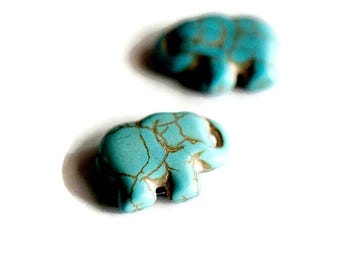 May include: Two small elephant-shaped beads in a bright turquoise color with dark brown veining throughout the surface. The beads are carved into a flat, stylized elephant silhouette with a hole near the trunk area for threading onto a cord.