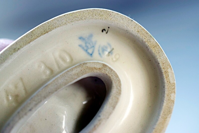 Puede incluir: Primer plano de la parte inferior de un objeto de cer&aacute;mica color crema. El borde tiene un borde moteado de color canela. Las marcas azules incluyen un dise&ntilde;o floral, el n&uacute;mero "2" y el n&uacute;mero "9". La palabra "BAVO" tambi&eacute;n es visible.