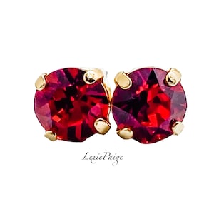 May include: A pair of small, round, red stud earrings with gold settings.