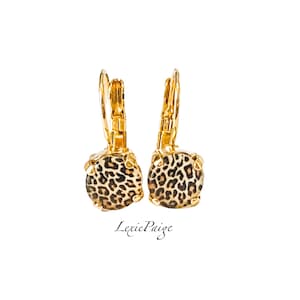 May include: Gold hoop earrings with a round, leopard print design. The earrings are made of metal and have a lever back closure.