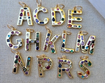May include: A set of gold-toned alphabet charms, each letter is encrusted with colorful gemstones. The letters are A, C, D, E, G, H, K, L, M, N, P, R, and S.