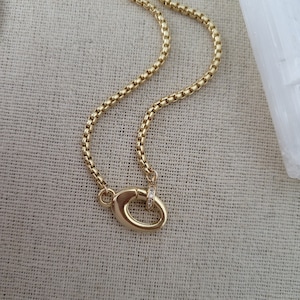 May include: A gold chain necklace with a small, oval-shaped clasp that has a single row of small diamonds.