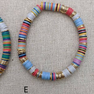May include: A colorful bracelet made of stacked, round, flat beads with gold accents. The beads are in shades of blue, pink, yellow, green, and white.