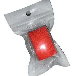 May include: A red, rectangular sponge in a clear plastic bag with a hole at the top.