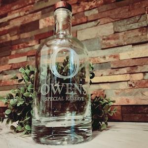 May include: A clear glass bottle with a cork top and a white etched design that says "Owens Special Reserve".