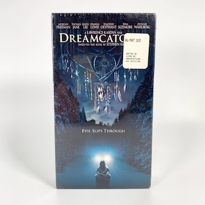 May include: A Dreamcatcher VHS tape featuring Morgan Freeman and Thomas Jane. The cover art depicts a dreamcatcher, a figure in a snowy forest, and the text "Evil Slips Through."