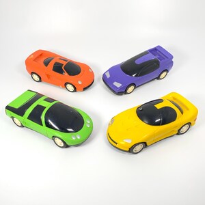May include: Four toy cars in different colors: orange, green, purple, and yellow. The cars are all different styles and have black windows.