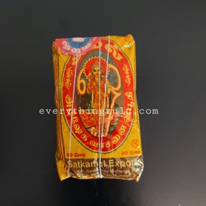 May include: A yellow and red package with a religious image and text. The package is wrapped with white string. The text "Satkamal Exports" is visible. The package weighs 80 grams.