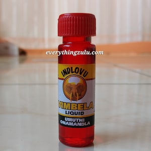 May include: A small, clear bottle filled with red liquid, topped with a red cap. The label features the text "INDLOVU" above an elephant graphic, and "VIMBELA LIQUID" and "UMUTHI ONAMANDLA" below. The website everythingzulu.com is printed on the bottle.