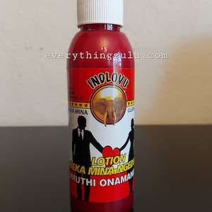 May include: A red bottle with a white cap, featuring the text "INDLOVU" and an illustration of an elephant. The label also includes silhouettes of a couple holding hands and the words "Lotion" and "BEKA MINA NGEN". The website "everythingzulu.com" is also visible.
