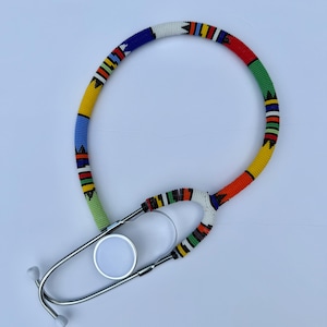 May include: A stethoscope with a vibrant, beaded design. The beads are arranged in patterns of blue, yellow, green, red, and white. The metal chest piece and earpieces are silver.