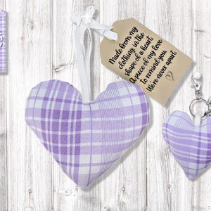Op de afbeelding: Een verzameling hartvormige items in een lavendel- en wit geruit patroon. Inclusief een groot gevuld hart, een kleine hartvormige sleutelhanger met een kwastje en een shirt met een hartomtrek. Een label luidt: "Made from my clothing..."