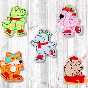 May include: A collection of five embroidered Christmas-themed animal patches. Includes a green alligator, pink flamingo, white hippo, orange fox, and a hedgehog, all wearing winter accessories and ice skates. The patches are in various colors and designs.