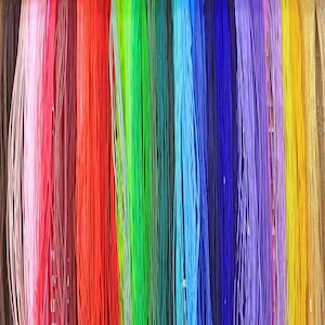 May include: A variety of colorful threads hanging in rows. The threads are arranged in a rainbow pattern, with red, orange, yellow, green, blue, indigo, and violet threads.