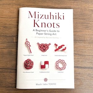 Puede incluir: Un folleto instructivo blanco titulado Mizuhiki Knots: A Beginner's Guide to Paper String Art. La portada muestra seis ejemplos de nudos rojos y blancos etiquetados como Figure-Eight, Awaji, Interlocked Awaji, Ume Blossom, Cobblestone y Loop knots.