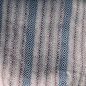 May include: A white fabric with a geometric pattern of black and brown diamonds. The fabric has a woven texture.